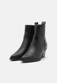 Botele negre din piele, de tip glezna, cu vârful ascuțit și un toc moderat. Au un design fără cusături și bucle pentru a fi ușor de încălțat.