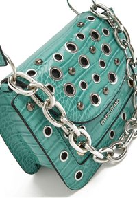 Tyrkysová kabelka z faux krokodýlí kůže s velkými kovovými očky a silným stříbrným řetízkovým popruhem, se zavíráním na klopu. Název značky "River Island" je vyražen.