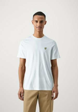 T-shirt bianco in cotone con collo tondo, con un piccolo logo giallo ricamato sul lato sinistro del petto. Maniche corte, texture liscia.