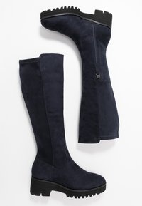 Bottes mi-mollet bleu marine en daim doux, avec une surface texturée, une semelle noire épaisse et une fermeture éclair latérale pour un enfilage facile.