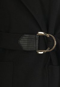 Cappotto nero con una cintura larga dotata di una fibbia in pelle testurizzata e un gancio in metallo color oro, che presenta un design pulito e moderno.