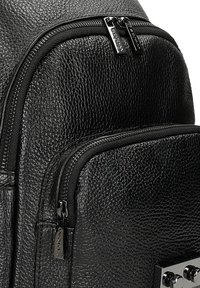 Czarna skórzana plecak z teksturowanym wykończeniem, podwójnymi kieszeniami na suwak i metalowymi akcentami. Kompaktowy i funkcjonalny design.