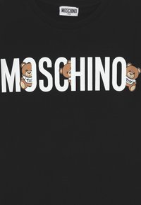 Černé teen triko Moschino s velkými bílými nápisy "MOSCHINO" a třemi hnědými medvídky, kteří mají na sobě trička "TOY" a jsou začleněni do písmen.