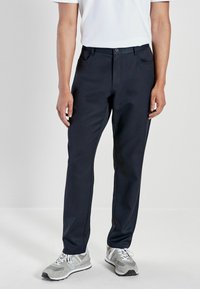Navy blue trousers with a straight cut, made from a smooth fabric. Features front pockets and a button closure, worn with gray sneakers.