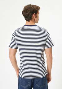 Camisa polo de algodón con rayas horizontales en azul marino y blanco, mangas cortas y un cuello acanalado en azul marino. La parte trasera presenta una textura suave y un ajuste relajado.