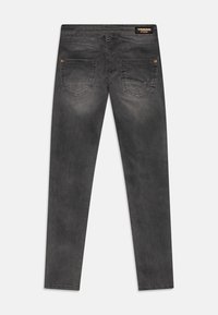 Černé džíny z denimu s úzkým střihem, obsahující dvě zadní kapsy a malou logo nášivku na pase. Ošuntělá textura s jemným vyblednutím.