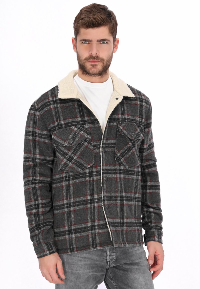 Chaqueta de cuadros grises con cuello de piel sintética crema, con dos bolsillos en el pecho y cierre de botones, hecha de una tela texturizada.