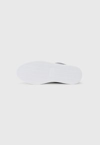 Mustad sneaker musta tekstureeritud valge kummiselt tallalt. Madala profiiliga disain, mis sisaldab siledat pealsed ja diskreetne logo kanna lähedal.