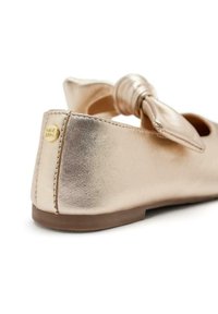 Ballerina flat metallizzato oro con punta rotonda, dettaglio in tessuto a forma di fiocco e logo sul tallone. Texture liscia con suola bassa.