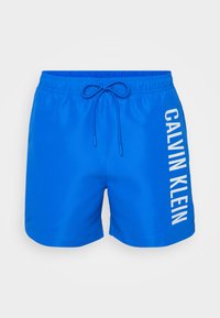 Blaue Schwimmshorts mit einem elastischen Bund, Kordelzug und weißem "CALVIN KLEIN" Logo, das vertikal auf der linken Seite aufgedruckt ist.