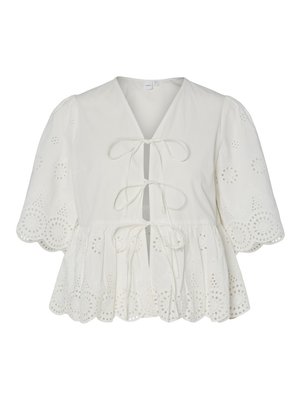 Valkoinen paita, jossa on silmäposliiniommel, liehukkeet hihansuissa, aaltoileva helma ja kolme etuosan nyöriä.