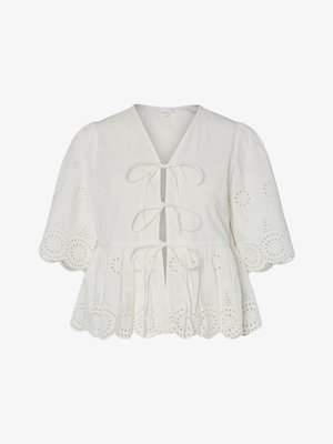 Valkoinen paita, jossa on silmäposliiniommel, liehukkeet hihansuissa, aaltoileva helma ja kolme etuosan nyöriä.