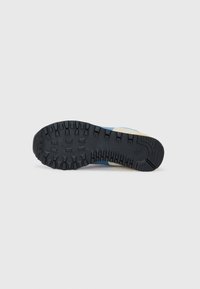 Sport shoe sole featuring a textured black rubber tread, with light blue and tan suede accents on the upper side. Designed for traction.