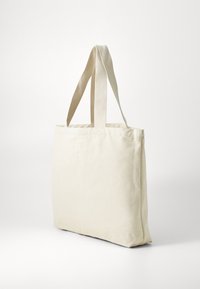 Beige lerretsnett med to solide håndtak, rektangulær form, flat bunn og ensfarget tekstur. Egnet for daglig bruk.