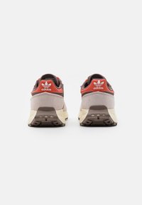 Adidas-sneakers med en grå och beige design, röda accenter, material av mocka och mesh, vadderad krage och strukturerad gummisula.