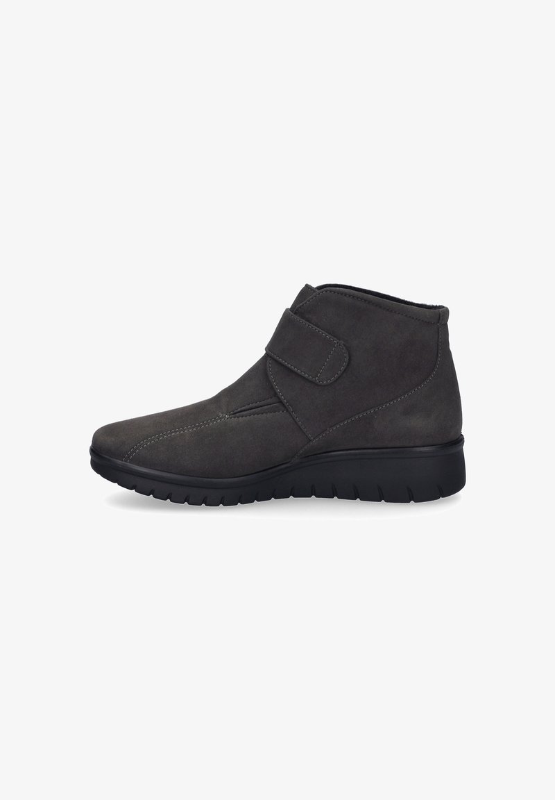 Graue Wildleder-Ankle-Boots mit einem Klettverschlussriemen, spitzer Zehenpartie und einer strukturierten schwarzen Gummisohle mit Rillen für besseren Grip.