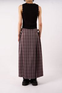 Μαύρο αμάνικο τοπ με στρας στους ώμους, συνδυασμένο με μια μακριά καρό φούστα σε αποχρώσεις του γκρίζου και του μπορντώ. Ορατές μαύρες πλατφόρμες μποτάκια.