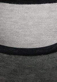 Gros plan sur un tissu noir et blanc avec une texture fine en maille et une bordure noire incurvée séparant les deux sections de couleur.