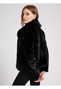 Veste en fausse fourrure noire avec un col montant, des manches longues et une coupe décontractée. Caractérisée par une texture douce et un design sans coutures.