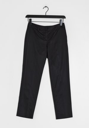 Schwarze, maßgeschneiderte Hose, die an einem schwarzen Kleiderbügel vor weißem Hintergrund hängt, mit Gürtelschlaufen und einem vorderen Reißverschluss.