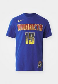 T-shirt de basketball Nike bleu avec « NUGGETS » et le numéro 15 en jaune et rouge, ainsi qu’un petit logo et une signature en bas à droite.