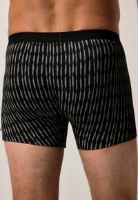 Boxer shorts a righe nere e grigie con una texture morbida, dotati di una vita elastica nera con la scritta "JP1880" in rilievo.