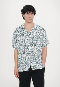 Πουκάμισο κοντομάνικο με κουμπιά σε λευκό χρώμα με σκουρόχρωμο μπλε τροπικό μοτίβο, που περιλαμβάνει φύλλα, κοχύλια και διάφορες παραστάσεις. Χαλαρή εφαρμογή.