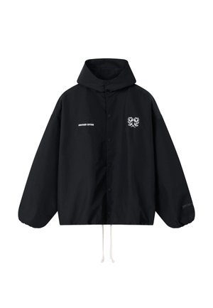 Schwarze Kapuzenjacke mit vorderen Knöpfen, weißen Kordeln, "ANOTHER COTTON" Schriftzug auf der linken Brust und zwei weißen Blumenlogos auf der rechten Brust.