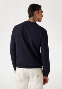 Felpa blu navy con scollatura rotonda e maniche lunghe, realizzata in tessuto morbido, presenta cuciture minime e una vestibilità comoda.