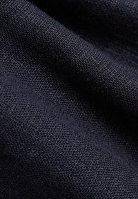 Tissu bleu marine avec un tissage texturé ; apparence douce ; poids moyen ; capte subtilement la lumière, révélant des motifs tissés et de la profondeur.