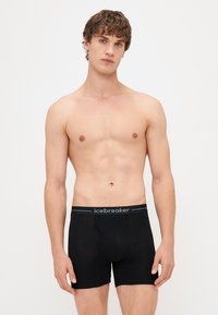 Boxer neri realizzati in materiale morbido, con un elastico in vita con il marchio "icebreaker". Il design è aderente e presenta una vita media.