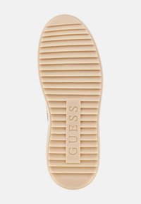 Talpă de cauciuc bej cu un model texturat de caneluri orizontale și un logo central embosat "GUESS".