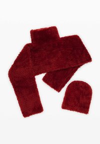 Fular roșu din blană artificială și căciulă asortată, având o suprafață moale și texturată cu o culoare uniformă, fără modele vizibile sau detalii de accesorii.