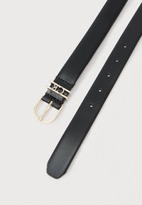 Μαύρη δερμάτινη ζώνη με χρυσό μεταλλικό κούμπωμα και διακοσμητική σχεδίαση του λογότυπου. Διαθέτει πολλαπλές τρύπες ρύθμισης και σχήμα με κομμένο άκρο.