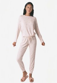 Světle růžový žebrovaný pyžamový set s drobnými květinovými vzory, s dlouhými rukávy, zúženými kalhotami a pasem na stažení. Měkká texturovaná látka.