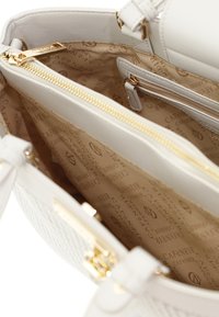 Borsa bianca con superficie testurizzata, hardware dorato e interno beige caratterizzato da un motivo con il nome e il logo del marchio. Tasche con zip incluse.