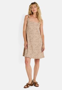 Vestido sin mangas de color beige con un patrón de rayas de cebra, hecho de tela ligera. Presenta tirantes ajustables y una silueta en A.