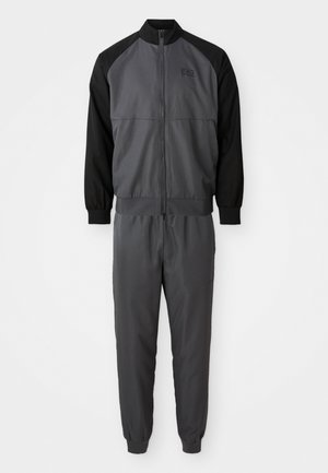 Gray track suit with a zip-up jacket featuring black raglan sleeves and matching tapered pants. Made from smooth, lightweight fabric.