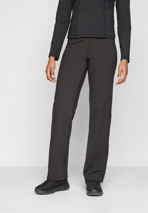 Pantalons de sport noirs en tissu lisse avec une coupe droite, dotés d'une ceinture confortable et de coutures latérales, associés à des baskets noires.