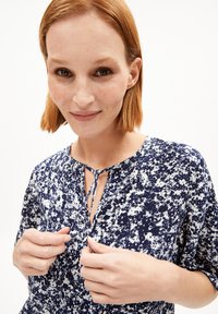 Marineblaue Blume-musterte Kleid mit kurzen Ärmeln, einem Schlitzkragen und einem Stoffbindeband als Akzent. Leichtes Material mit einer weichen Textur.