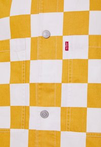 Żółto-biała koszula w kratę z dwoma kieszeniami, srebrnymi guzikami i małą czerwoną metką Levi's po lewej stronie. Wykonana z bawełny o gładkiej fakturze.