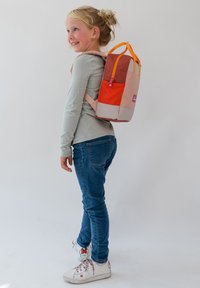 Élénk színű hátizsák narancssárga, rózsaszín és bézs anyagból, téglalap alakú és strapabíró pántokkal. Cipzáras záródás lila kiegészítőkkel.