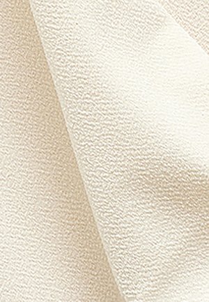 Cremefarbenes, strukturiertes Gewebe mit einer weichen, leicht erhöhten Oberfläche, gefaltet, um Tiefe und Variationen im Webmuster zu zeigen.