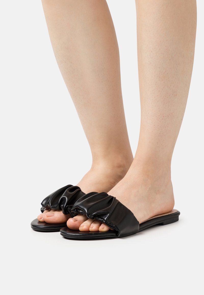 Sandali neri con suola piatta, upper sintetico arricciato, design aperto nella parte anteriore e senza hardware o motivi visibili.