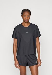 Μαύρο αθλητικό T-shirt και σορτς από υφή, διαπνέον ύφασμα. Διαθέτουν διακριτικό τριγωνικό μοτίβο και μικρό λογότυπο στο στήθος.