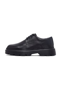 Chaussure oxford en cuir noir avec une finition texturée, bout rond et épaisse semelle en caoutchouc noir dotée d'un motif de semelle rugueux.