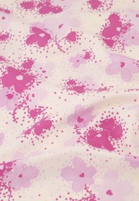 Lichte stof met roze bloemen en harten op een crème achtergrond, met variërende tinten roze stippen voor textuur en detail.