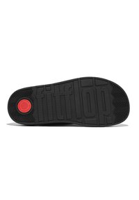 Black rubber shoe sole with textured grip pattern, featuring a red circular logo and embossed branding "fitflop" across the surface.