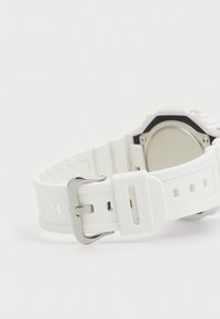 Bracelet de montre en silicone blanc avec une boucle en métal argenté, présentant une texture lisse et un design perforé pour la ventilation.