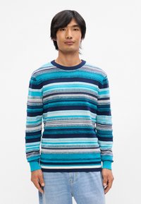 Pull rayé dans des nuances de bleu et de marine, mettant en avant un col rond et des poignets côtelés. Tricot texturé avec des largeurs de rayures variées.